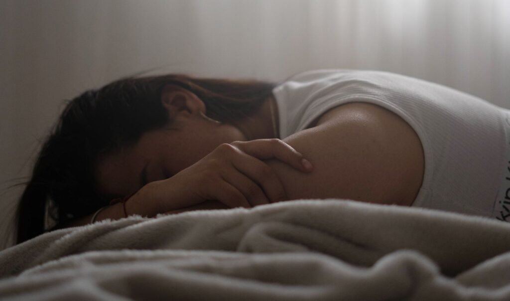 A woman peacefully sleeping in a sunlit bedroom, wrapped in a soft blanket.